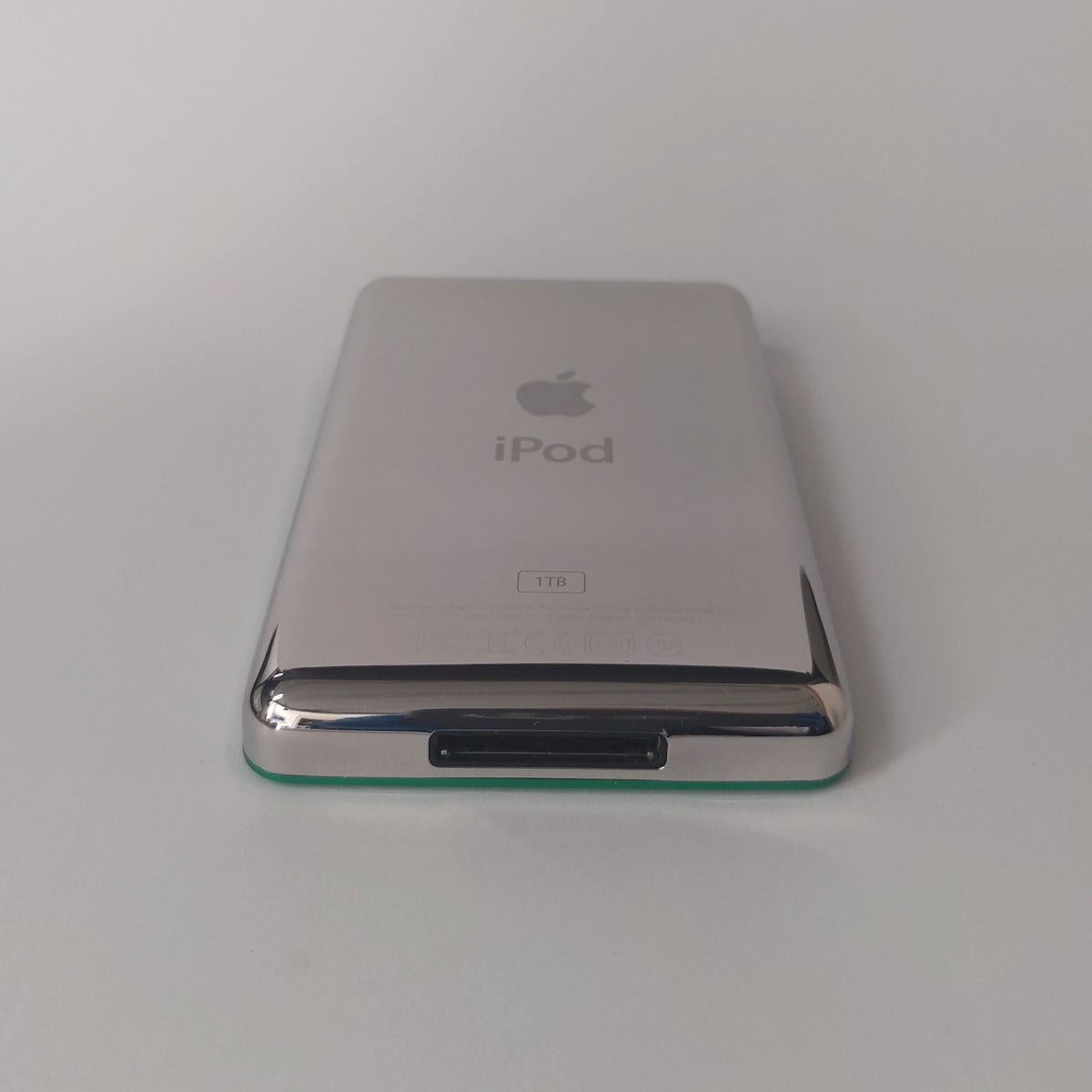 Rear view of a green iPod Classic showing its polished silver back with iPod and 1TB engraving