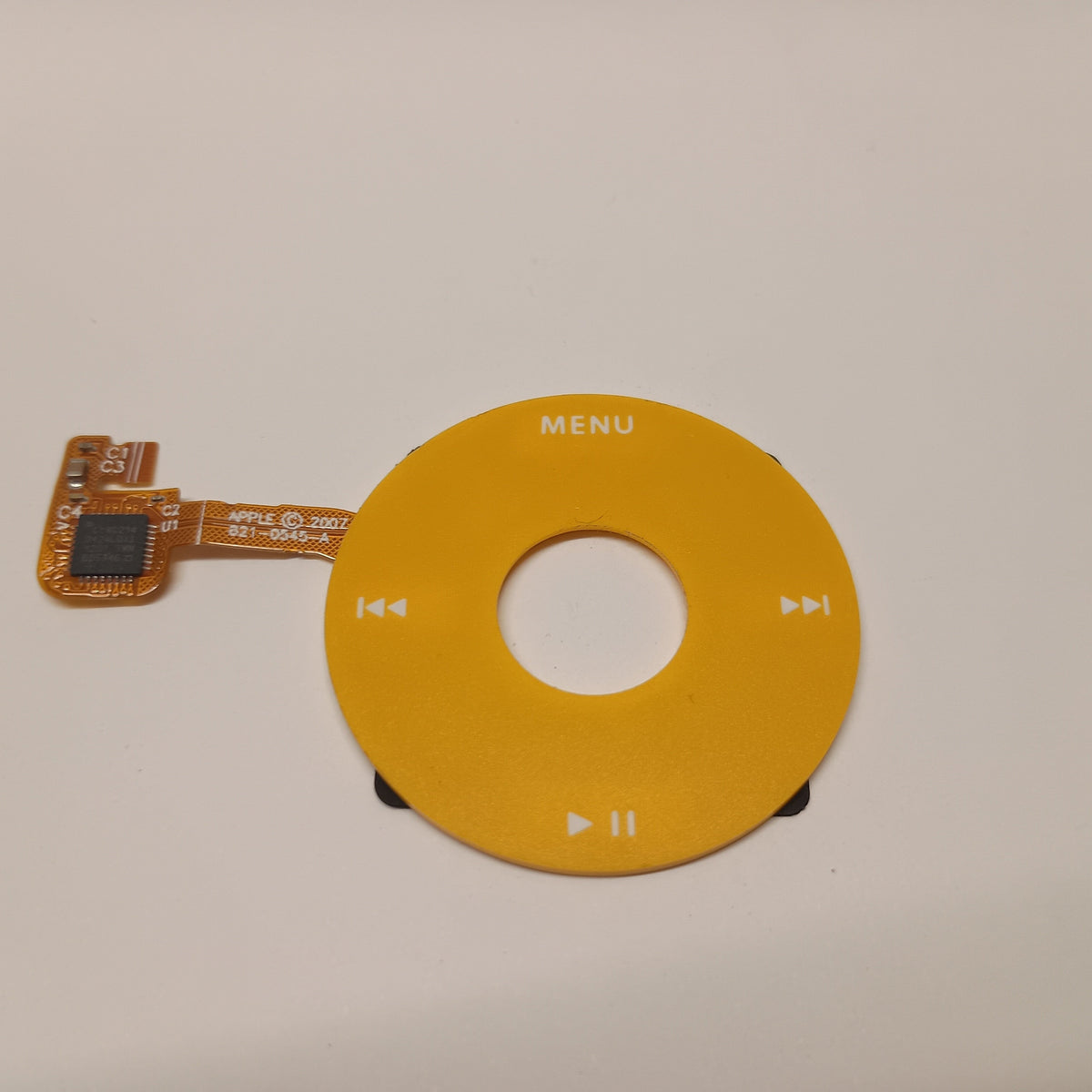 Yellow iPod Classic replacement click wheel with white control markings and an attached orange ribbon cable