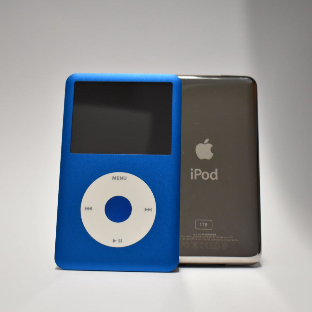 Front and rear views of blue iPod Classics, showing the white click wheel and polished silver back with 1TB engraving