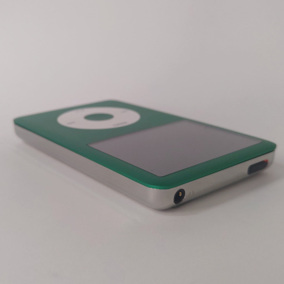Angled view of a green iPod Classic with a white click wheel and polished silver rear housing