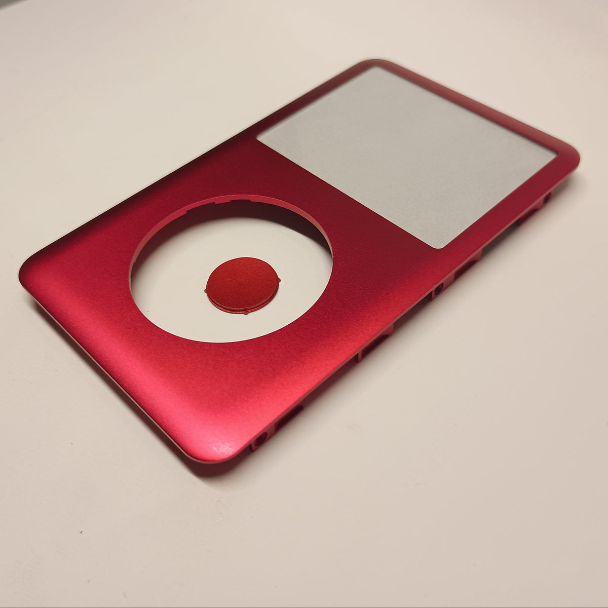 Angled view of a red iPod Classic replacement front housing with a matching centre button