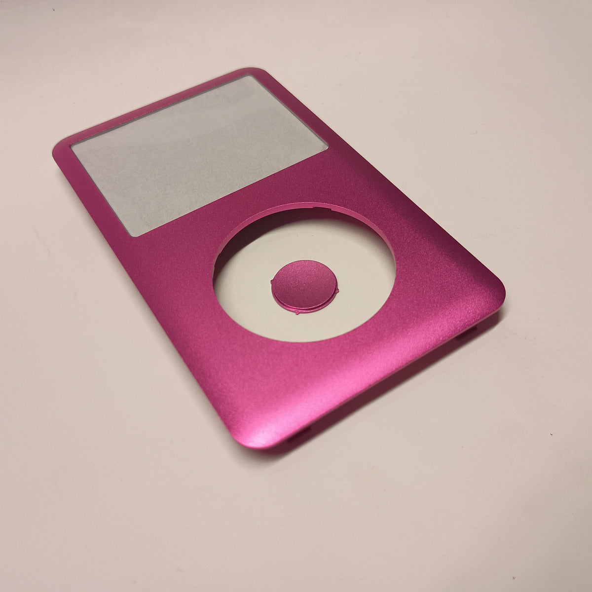 Pink iPod Classic replacement front housing and matching centre button, shown at an angle from the lower end