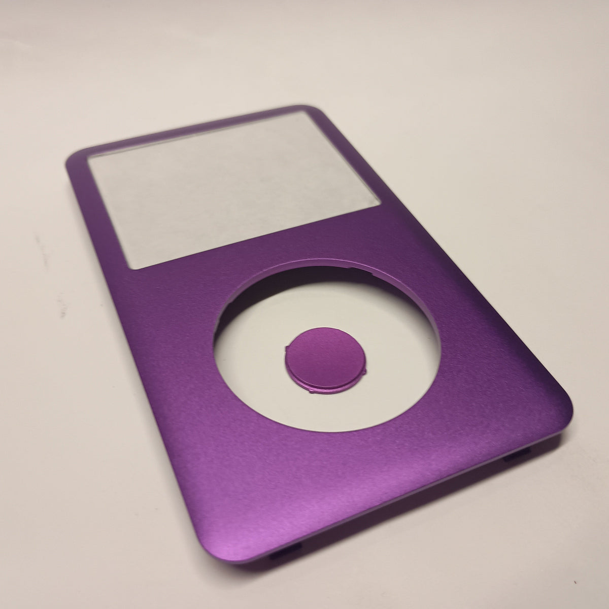 Purple iPod Classic replacement front housing and matching centre button, shown at an angle from the lower end