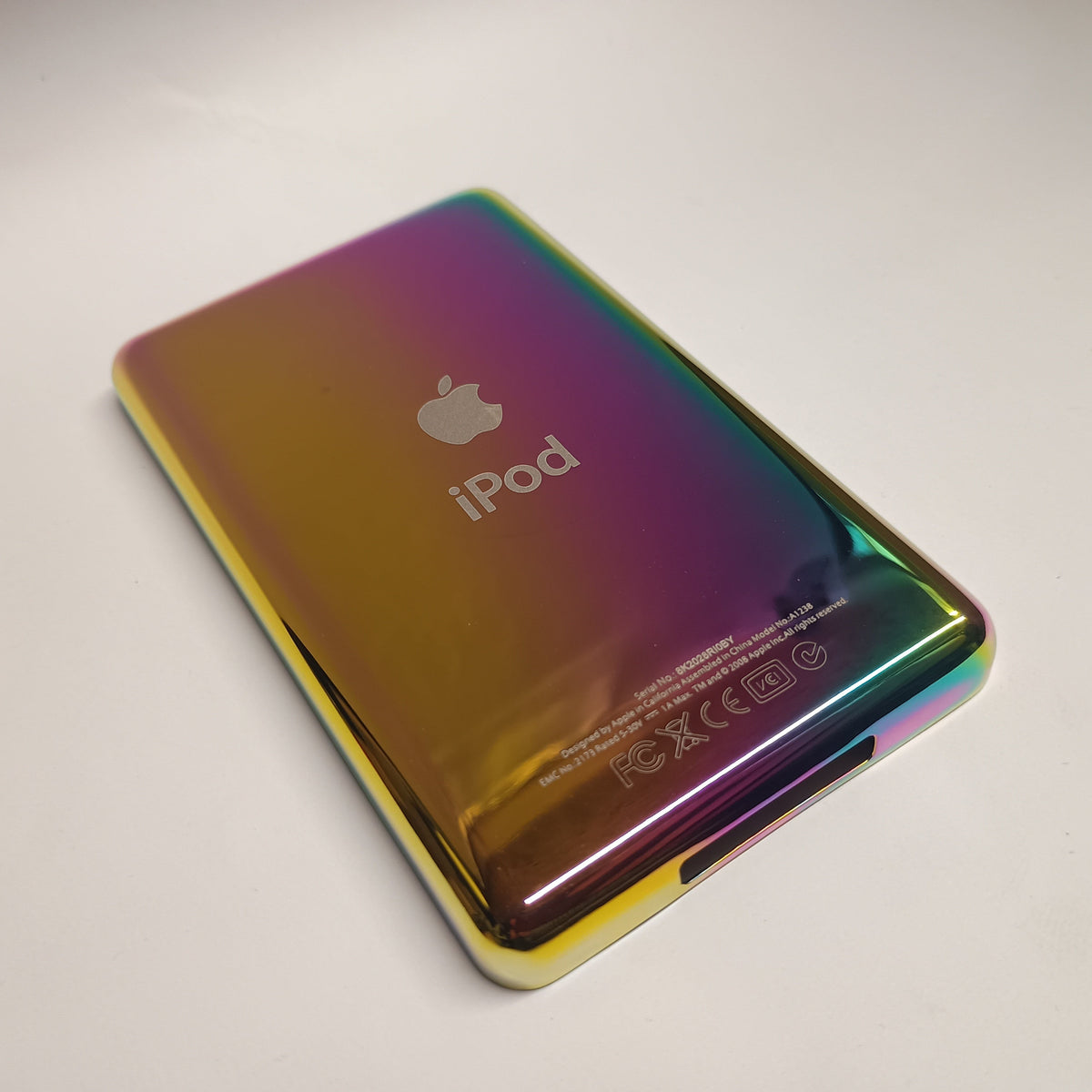 Angled view of a polished rainbow-finish iPod Classic replacement rear housing with Apple and iPod engraving