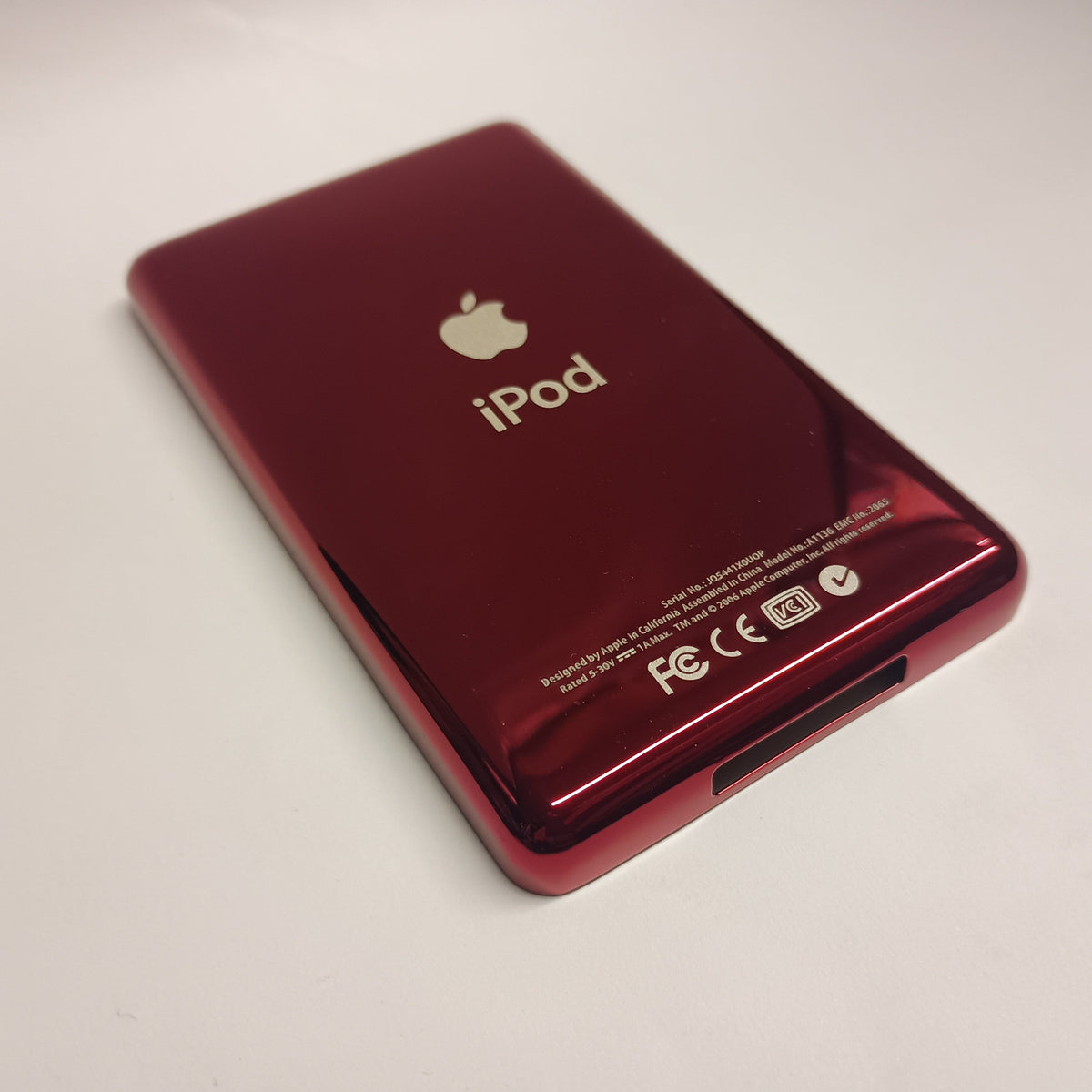 Angled view of a polished red iPod Classic replacement rear housing with Apple and iPod engraving